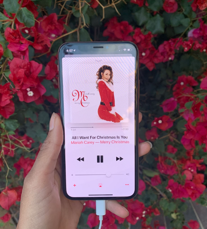 With red flowers in the background, Mariah Carey’s “All I Want For Christmas Is You” plays on an iPhone. According to Billboard, it was the top Holiday Song for 30 weeks last winter.