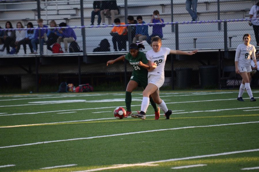 Megha Salve (9) fights for the ball against a Pinewood player. The teams sold purple shirts with I wear purple for... blazoned across their backs to show respect for those who have cancer.
