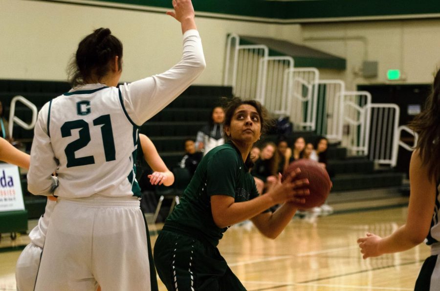 Varsity girls basketball captain Akhila Ramgiri (12) tries to score over a James Lick defender. The girls end their season with an overall record of 13-10. 