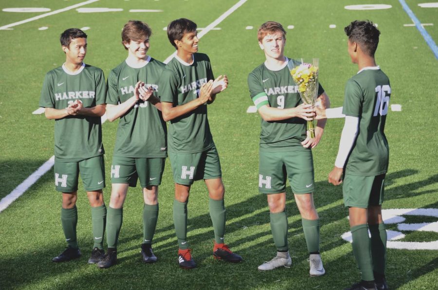 Shomrik Mondal (11) hands a bouquet to varsity captain Jared Anderson during the halftime senior recognition ceremony. The ceremony honored Edwin Su, Jack Dawson, Krish Kapadia and Jared. 