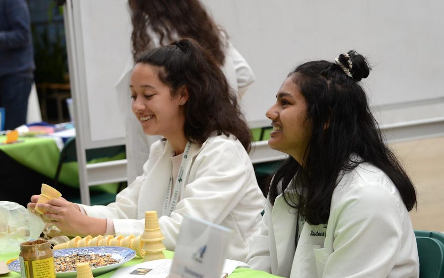 WiSTEM volunteers Emma Dionne (10) and Vidya Jeyendran (10) lead one of the tables for WiSTEMs food-based modeling activity. The symposiums scheduled events included exhibit tables, keynote speakers, student and alumni panels, poster presentations and a variety of other activities and workshops.
