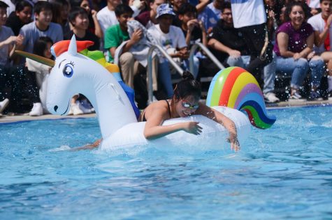 Katie Li (10) pulls herself up onto the inflatable unicorn float during todays regatta race. Katies class, the sophomores, won the race, followed by the freshmen in second and the seniors and juniors in third.