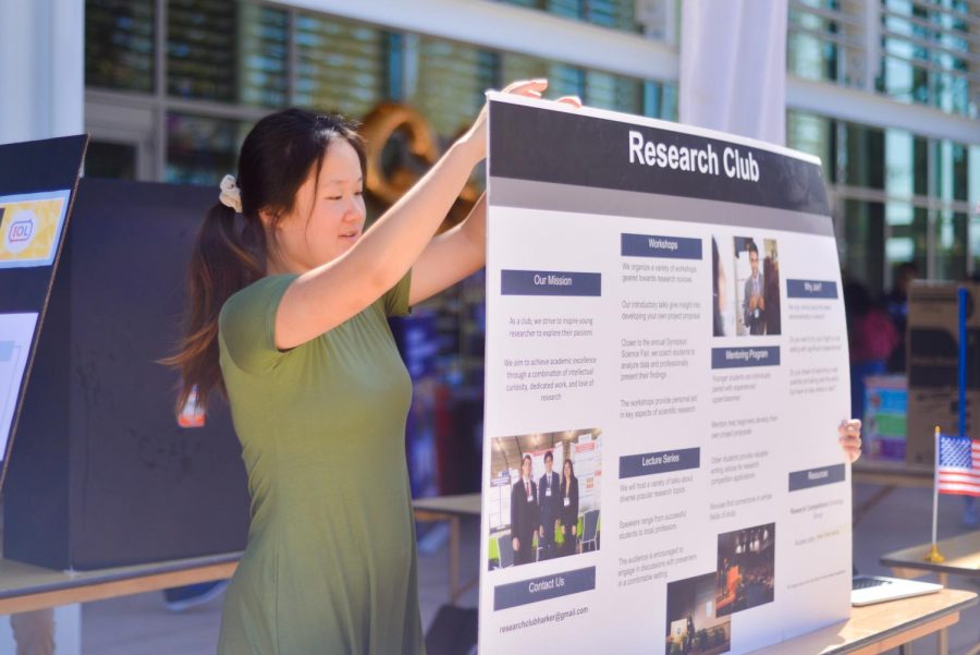 Cynthia Chen (12) readjusts the board for Research Club at Club Fair today during lunch. Club Fair featured a variety of student organizations, ranging from STEM to business to student activism groups, and invited students to sign up for clubs that aligned with their interests. 