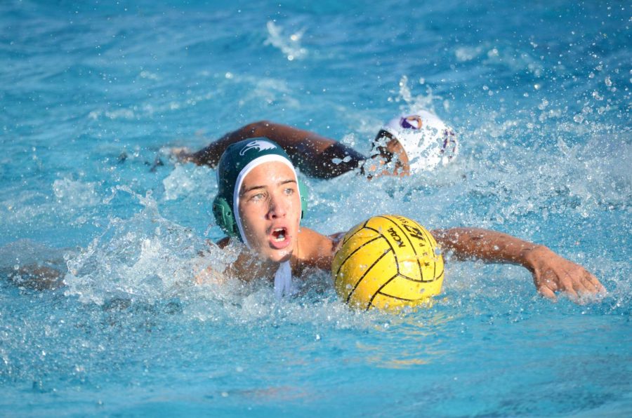 Drake Piscione (9) reaches for the ball during a boys water polo game. 