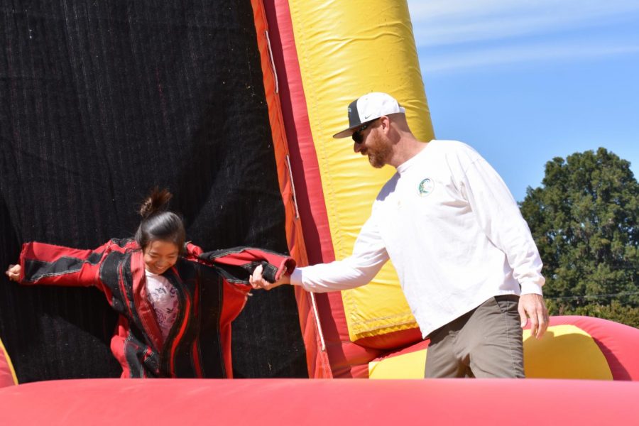 Director of Sports Medicine and Sports Performance Jaron Olson helps a middle school student off of the velcro wall. This new attraction was one of many that were introduced at this years Family & Alumni Picnic.