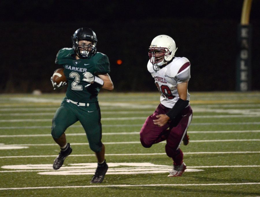 Running back Devin Keller (12) carries the ball down the field, chased by a player from Lowell High School. The Eagles played Lowell on Sept. 13 and ended with a tie at 15-15.