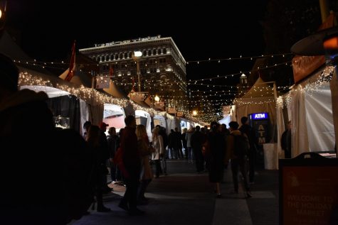 Customers walk through the sidewalk adjacent to Seventh Street. The Holiday Market opened yesterday and features local hand-crafted goods.