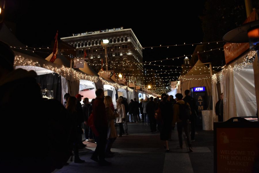 Customers walk through the sidewalk adjacent to Seventh Street. The Holiday Market opened yesterday and features local hand-crafted goods. 