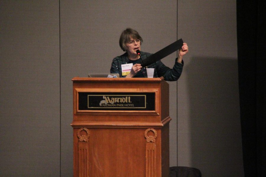 Mary Beth Tinker holds up a signed black armband to an audience of student journalists at the JEA/NSPA convention, a similar piece to the original black armbands she wore to protest the resulting casualties of American involvement in the Vietnam War.