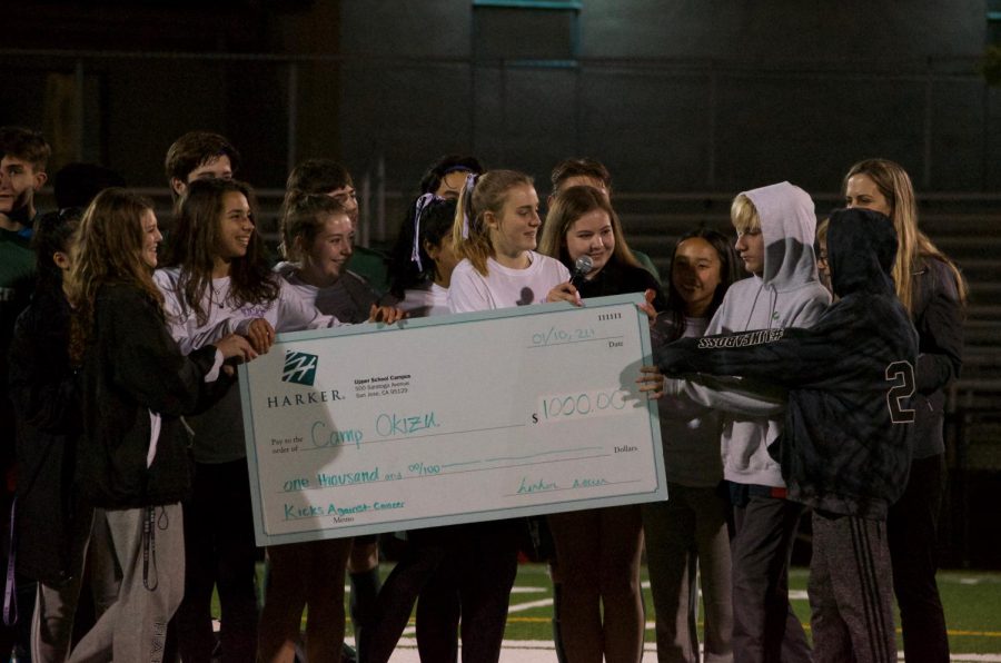 Members of the girls varsity soccer team hand a faux check to campers from Camp Okizu after Ashley Barth (10) gives a brief speech expressing her appreciation for the Harker community for supporting Kicks Against Cancer. 