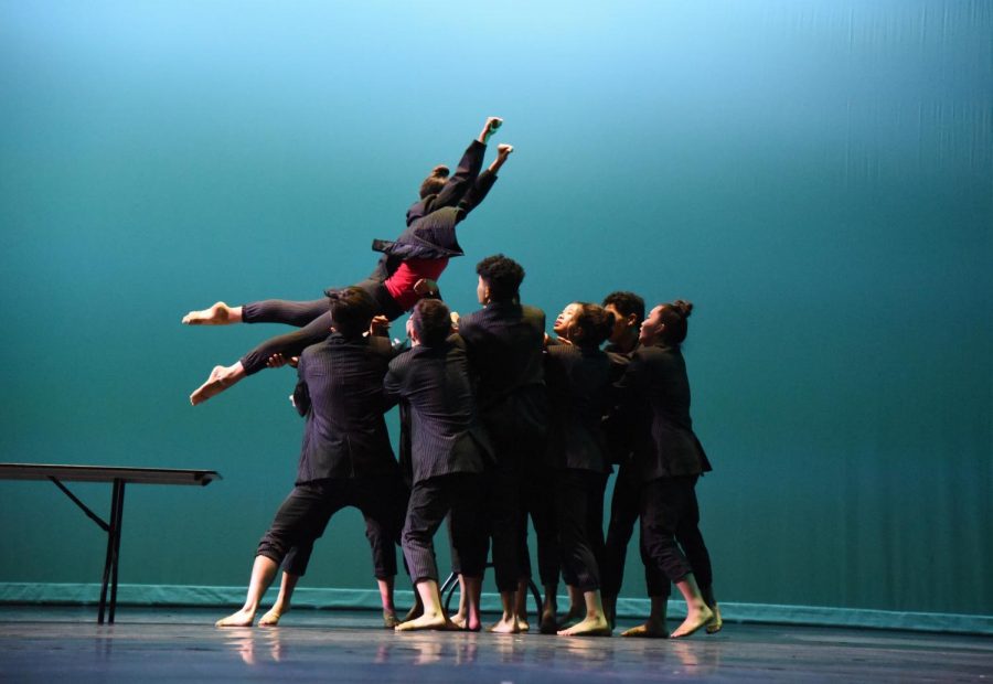 Junior Zoe Kister jumps into a crowd of dancers. Zoe is one of eight student choreographers.