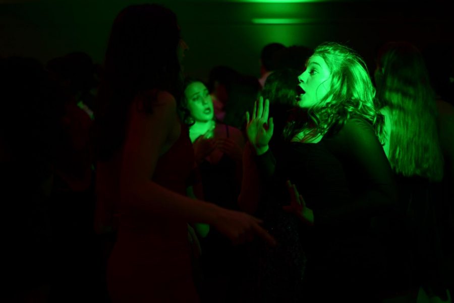 Junior Calais Poirson dances and sings with the crowd near the DJ booth, where the L.E.D. lights emit a variety of colors around the room.
