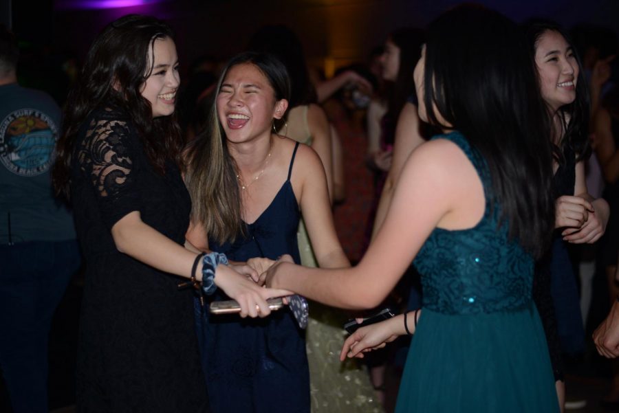 Seniors Anna Miner, Emiko Armstrong and Allison Lee hold hands as they dance and smile during a slow song.