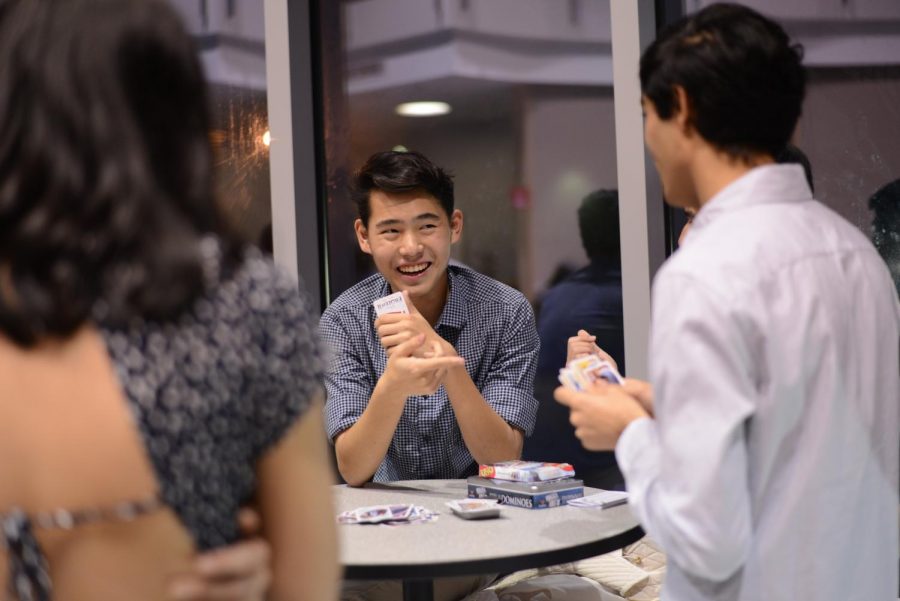 Bennett Liu (12) smiles as he plays card games with his friends, another activity set up by the senior council at the dance.