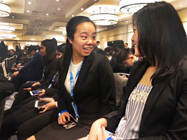 Clarice Wang (10) and Melody Luo (10) chat about past experiences at DECA conferences while waiting for the opening ceremony to start last Friday evening.