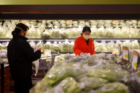 Two women, both wearing protective masks, select vegetables at 99 Ranch Market in Cupertino on Sunday evening. Due to the global novel coronavirus outbreak and the recent confirmation of cases in Santa Clara County, stores around the Bay Area have been experiencing shortages of masks.