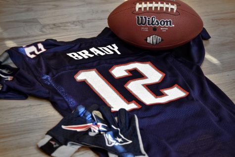 A Tom Brady jersey, along with a football and receiver gloves. As a result of Brady's move from the Patriots to the Buccaneers, there are many different predictions regarding how this transition will affect both teams.