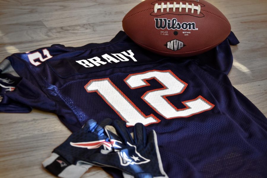 A Tom Brady jersey, along with a football and receiver gloves. As a result of Bradys move from the Patriots to the Buccaneers, there are many different predictions regarding how this transition will affect both teams.