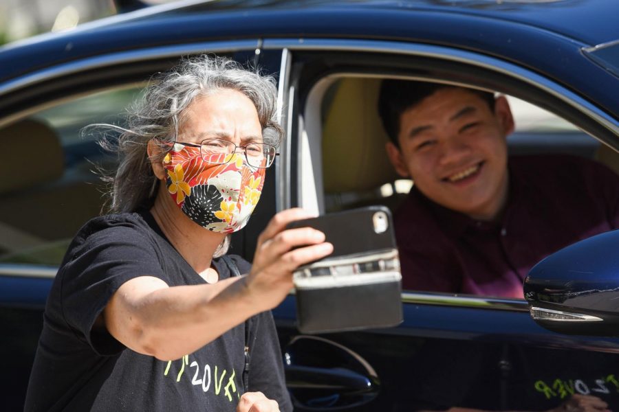 Upper school computer science teacher Marina Peregrino and Eric Fang (20) pose for a selfie at the drive-thru. As seniors drove through, they were able to return items and receive their gifts from masked faculty members stationed in tents.