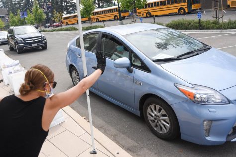 Upper school librarian Meredith Cranston waves to a student driving by. Students drove by the front loading zone on Saturday to receive supplies for the upcoming school year.