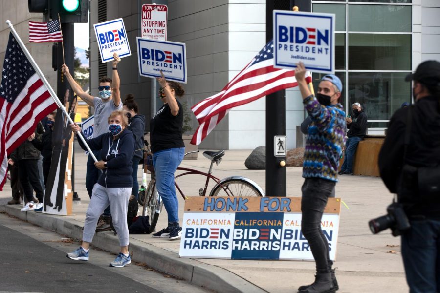 People stand outside the San Jose City Hall today afternoon, waving American flags and celebrating Joe Bidens presidential win.