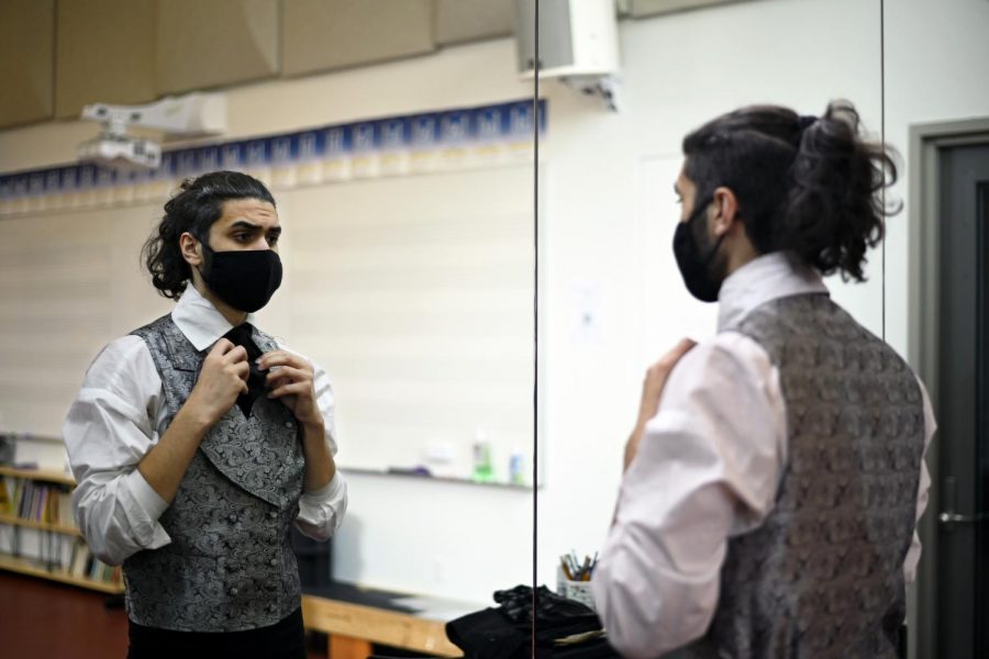 Alex Kumar (12) faces the mirrors in the dressing room as he adjusts his costume. Alex plays the role of protagonist Jean Valjean.