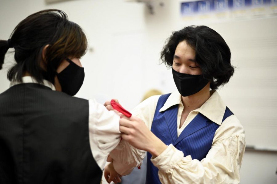 Daniel Wu (11), who plays Courfeyrac, ties a red armband for Sarah Raymond (12) in the dressing room. The armband was worn by select cast members to mark them as revolutionaries.

I think it was really great to show the power of collaboration and effort. Without everyone involved spending lots of time and being willing to be patient and to learn, it never couldve happened, Daniel said. 