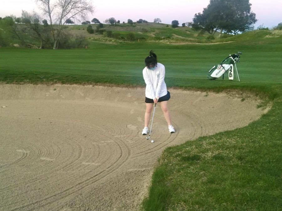 Jessica Zhou (10) prepares to hit a bunker shot at a practice round at Cinnabar Hills Golf Club last week. Following the upper schools safety protocols for athletes, players are required to wear masks and social distance at all times.