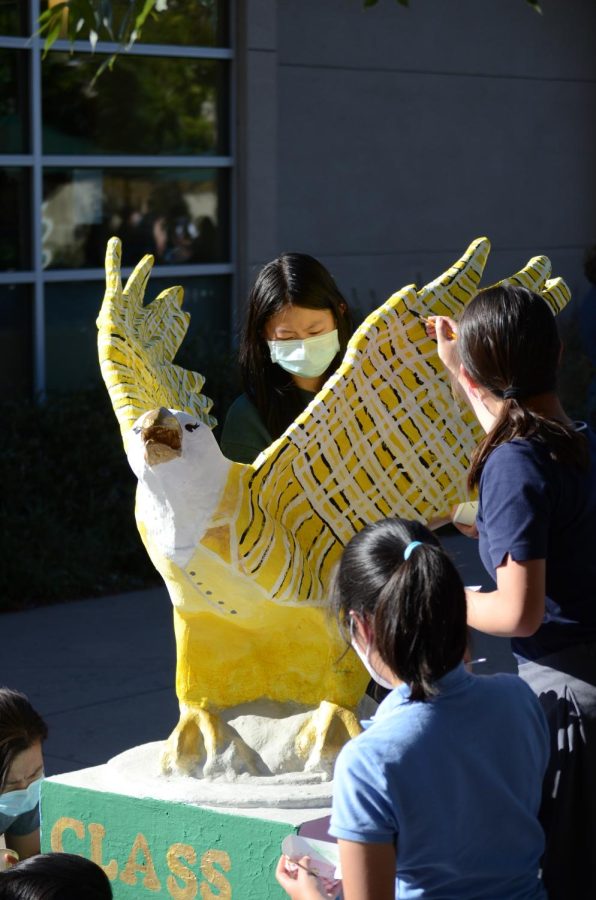 Ainslie Chen stands behind the freshman eagle while Lindsey Tuckey paints the eagle wings. This years freshman class color is white.
