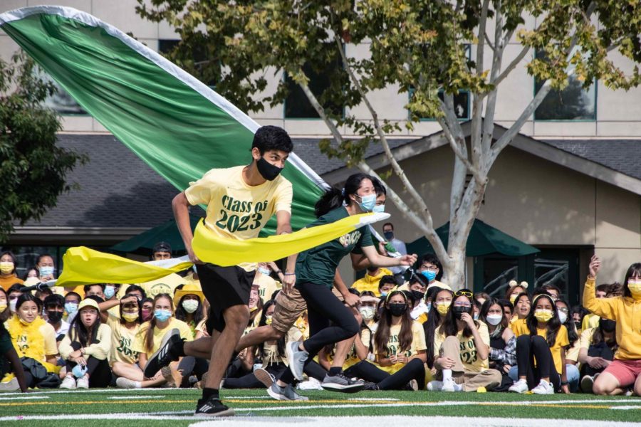 Homecoming representatives Atri Banerjee (11) and Nicole Tian (12) race across Davis Field with class flags as a part of the flag run activity. The relay-style contests for Homecoming representatives was prepared by HSLT. 