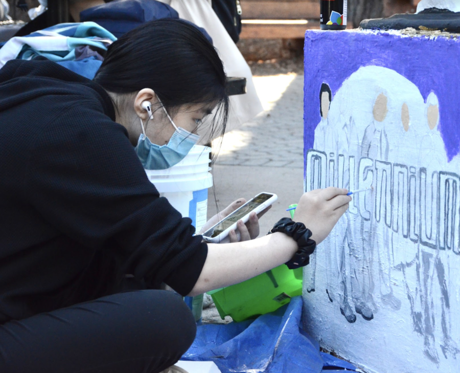 Angelina Hu (10) paints the Backstreet Boys' album "Millenium" on the side of the sophomores' class eagle.