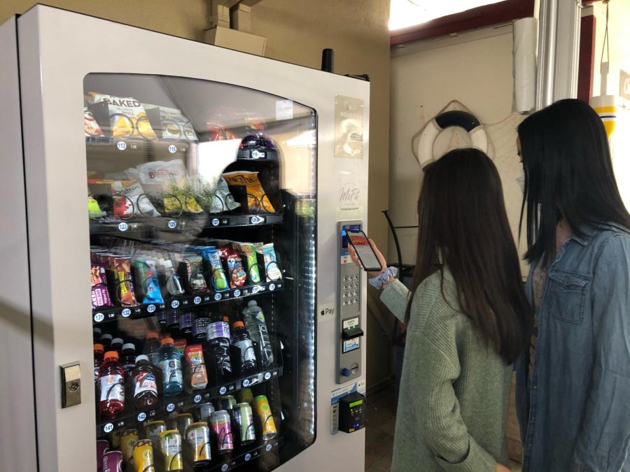 Shayla He (10) and Ella Lan (10) purchase an item from the new vending machine in Manzanita Hall. The new vending machine contains a total of 35 different items, ranging from chips and energy bars to drinks and even hand sanitizer.