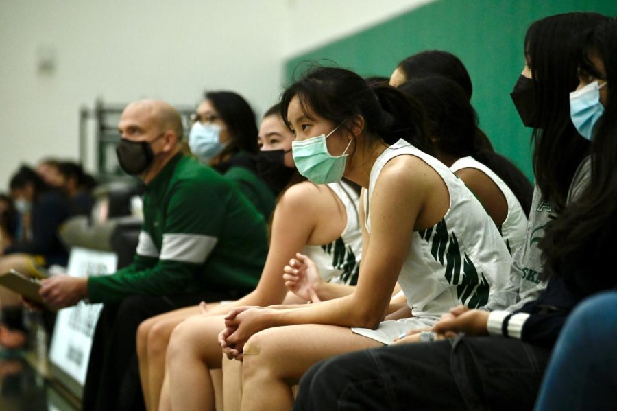 Intently watching the court from the sidelines, Alexa Lowe (12) sits with her other varsity girls basketball teammates.