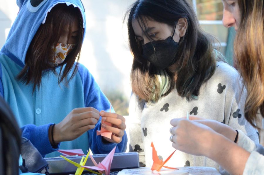 Vivian Bi (11) teaches Makayla Aguilar (11) how to fold a paper crane. The LIFE Board organized a project to fold 1000 paper cranes for upper school math teacherJane Keller, who was recently diagnosed with cancer.