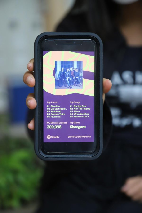 Kathy Xu (11) holds out her phone, which displays the final page of her 2021 Spotify Wrapped statistics. Spotify Wrapped released this year on Dec. 1 and showed user statistics from the past year in a multi-page story format.
