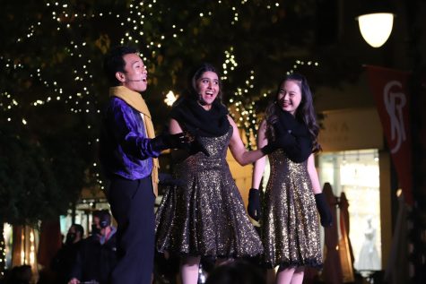 Downbeat members Kris Estrada (11), Samvita Gautham (11) and Shayla He (10) smile as they introduce the performances at Santana Row on Tuesday. Upper school performing arts groups Downbeat, Kinetic Krew and Harker Dance Company traveled to Santana Row on Tuesday evening to perform festive routines filled with holiday cheer.
