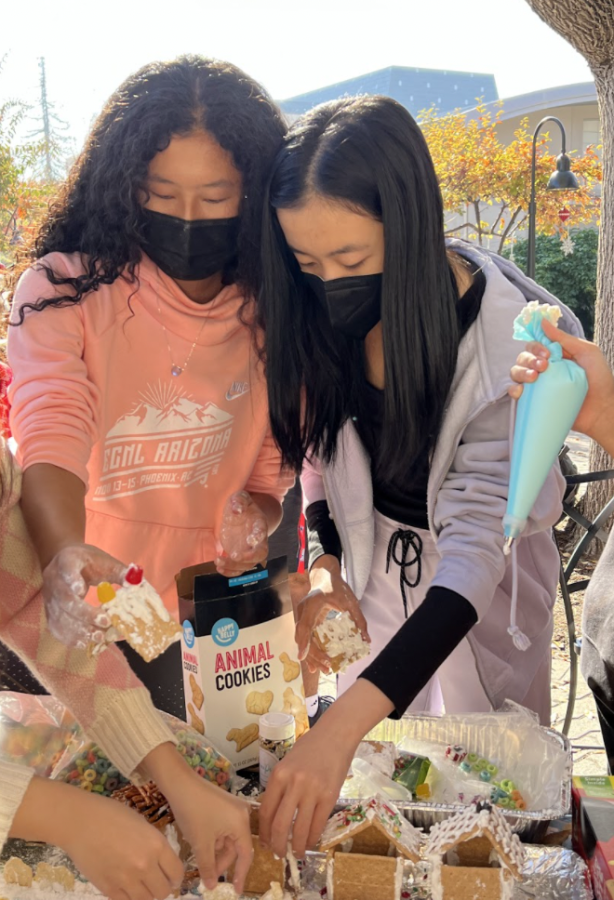 Sophomores Cynthia Wang and Ella Lan decorate a gingerbread house together. Students used a variety fo edible goods to personalize their gingerbread houses.