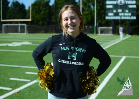 Imogene Leneham (12) poses on Davis Field with gold pom-poms. As captain of Harkers cheerleading team this year, Imogene is in charge of choreographing sections of new routines and teaching them to her fellow cheerleaders.
