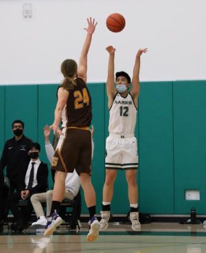 Charles Ding (12) attempts a three-pointer from the corner during the varsity boys basketball teams match against Gunderson High School. The boys won 63-51.