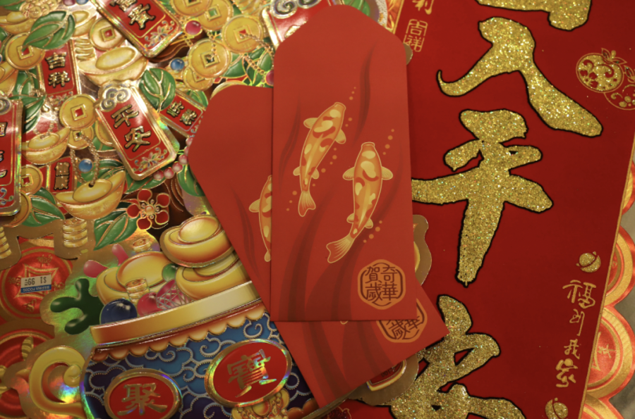 Traditional red envelopes with drawings of koi lay on colorful Lunar New Year decorations. 
