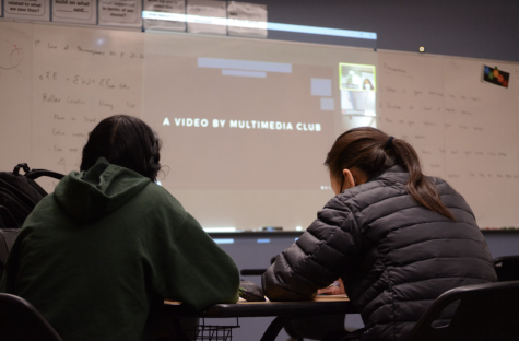 Medha Yarlagadda (10) and Ashley Hong (10) watch the Multimedia Club video during the school meeting last Friday. During the meeting, students announced upcoming activities such as the Lunar New Year dragon dance competition and the Emerald Brass Quintet concert.
