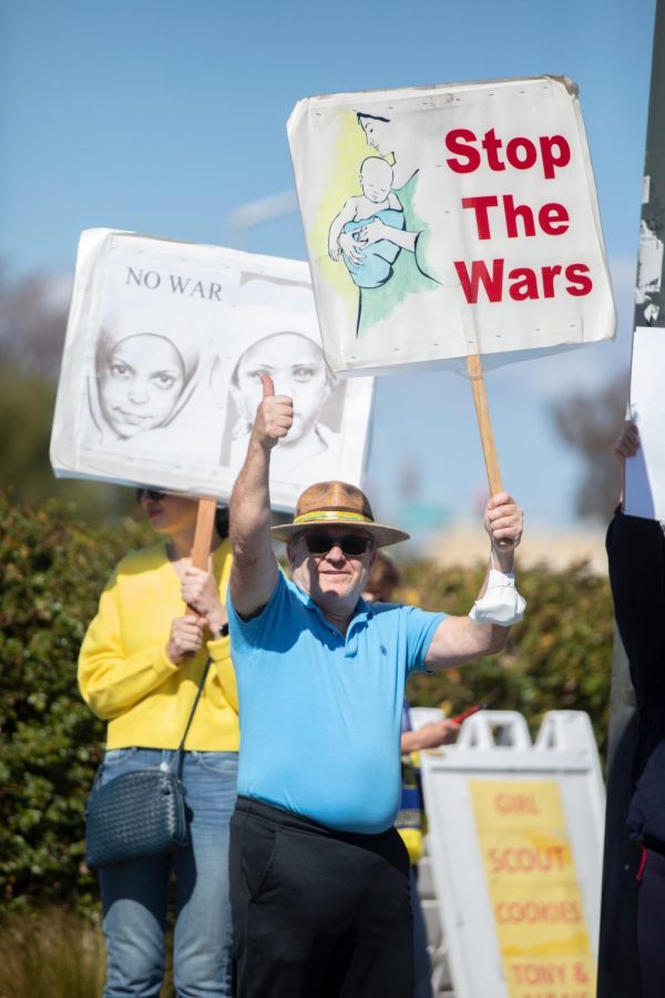 A demonstrator holds up a sign reading Stop the Wars. Protesters could bring their own signs or use one provided by the San Jose Peace and Justice Center.