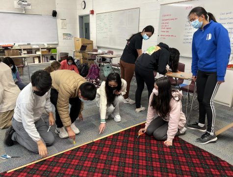 Key club members Ethan Liu (10), Andrew Liang (9), Lucy Ge (12), Jacqueline Soraire (10) and Olivia Xu (10) measure and mark fabric before cutting it into scarves. All scarves will be given to the homeless through The Toiletri Project.