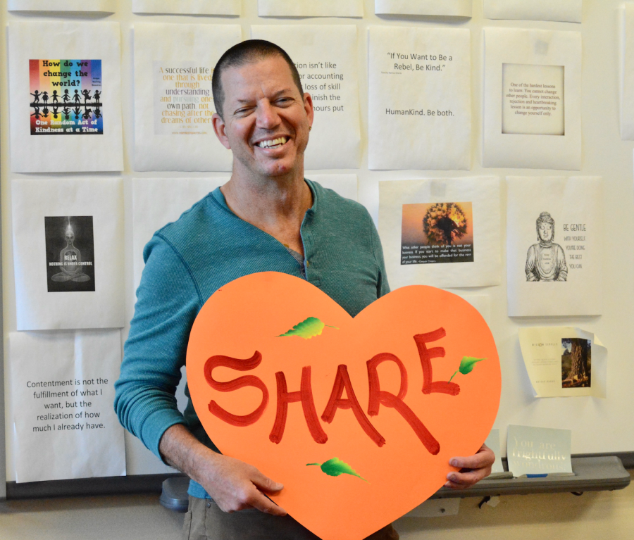 Upper school mathematics teacher Bradley Stoll holds a heart shaped paper cut-out with the word share painted over it. Ever since becoming vegan in 2014, Stoll has discovered new ways of cooking and sharing his baked goods with others.