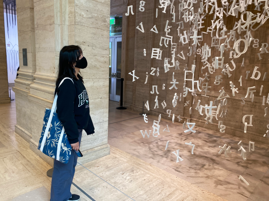 Gloria Zhu (12) observes Collected Letters by Chinese artist Liu Jianhua. The piece is made of over 1,600 porcelain letters and fragments of Chinese characters. 