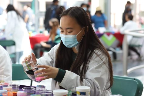 WiSTEM club member Michelle Jin (11) pours water into a cup of magic sand. WiSTEM officers and members organized the Research Symposium under the guidance of club adviser and upper school science department chair Anita Chetty.