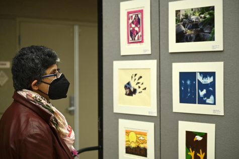 Upper school mathematics teacher Caren Furtado observes several works of photography and art at the Artstravaganza exhibits. Campus art and writing exhibition Artstravaganza displayed student artwork and literature from the past year.