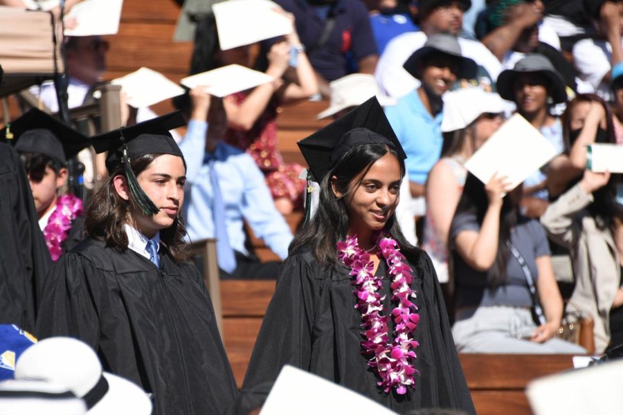 Minali Kapadia (22) walks alongside Josh Field (22) during the starting progression to their seats. The class of 2022 walked down in a single file line before doubling up to walk down the stairs.