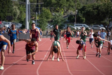 Andrew Fu (11) runs with the baton in hand towards relay race teammate Rigo Gonzales (11). The boys relay team placed seventeenth at the State Championships on May 28.