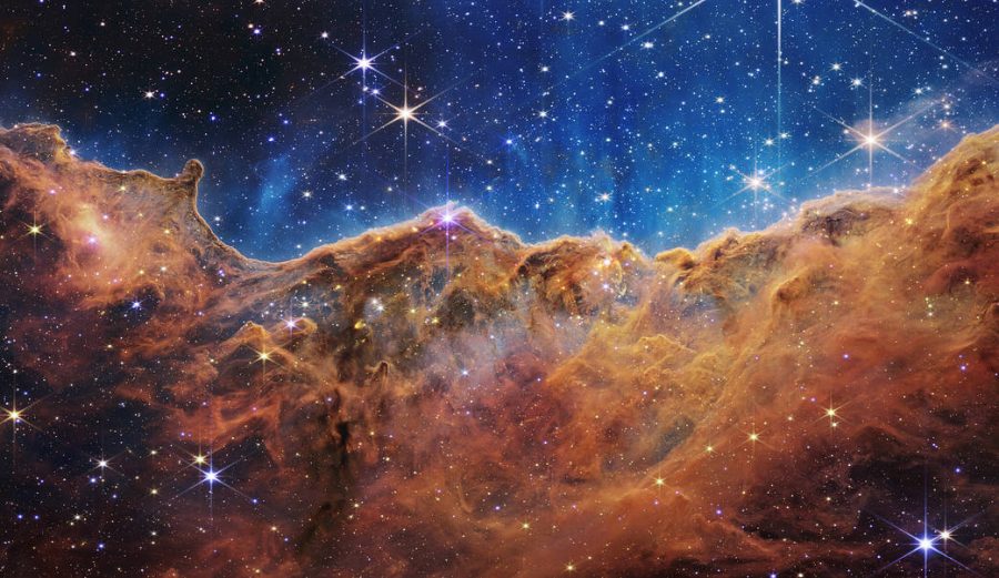 An image of cosmic cliffs in the Carina Nebula, taken by NASAs James Webb Space Telescope. With more and more technologies pushing the limits of space exploration, two Harker Aquila writers argue for the pros and cons of exploring our universe. 